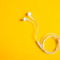 韩漫网社区专员阿哲戴着耳机处理用户反馈邮件，桌面上贴着待办便签，屏幕显示收件箱列表与深色界面